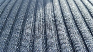 Koyu gri ya da kömür kaplı tekstilin detaylı makro fotoğrafı. Örgü kumaşın belirgin bir dikey deseni ve metalik ipliklerden ince bir parıltısı var..