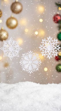 Narin beyaz kar tanelerinin, parıldayan altın ve kırmızı süslemelerin ve ışıldayan bokeh ışıklarının yer aldığı güzel bir Noel arkaplanı karlı bir ön planla büyülü bir kış tatili atmosferi yaratıyor..