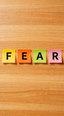 Her birinde tek bir harf olan dört canlı yapışkan nota açık kahverengi ahşap bir yüzeye yatay olarak dizilmiş 