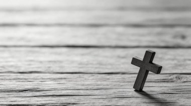 Küçük, basit bir ahşap haç, klasik siyah ve beyaz estetik yapılmış, dokulu, yıpranmış bir kereste yüzeyinde dimdik durur..