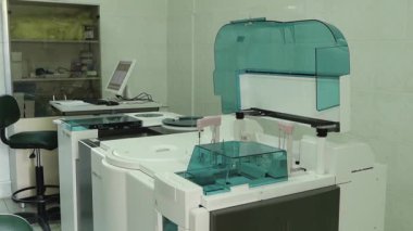 Bir Cobas e 411 analizcisi ve bir teknisyen çalışma alanının yer aldığı profesyonel bir tıbbi laboratuvarın geniş bir görüntüsü. Temiz, steril ortam gelişmiş biyokimyasal testler, kan analizleri ve tanı araştırmaları için donatılmıştır..