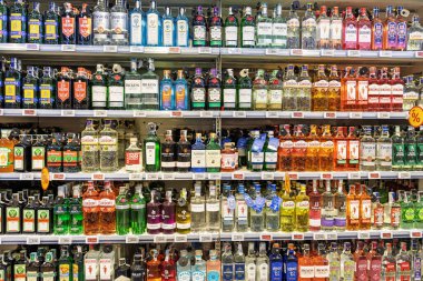 Auchan mağazasında Beefeater, Gordons ve Bombay Sapphire gibi popüler cin markaları da dahil olmak üzere çeşitli ruhlar sergileniyor. Perakende hipermarketinin alkol bölümünde fiyat etiketli raflar..