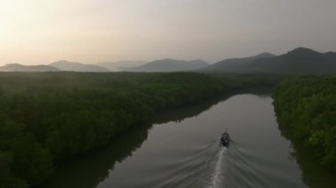 Gün doğumunda Tayland 'ın Koh Yao Yai adasında nehirden geçen uzun kuyruklu teknenin hava görüntüsü. Mangrove ormanı ve tepeleri.