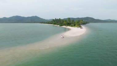 Havacı romantik çift, Tayland 'ın Koh Yao Yai kentindeki tropikal beyaz kumsalda yürüyor.