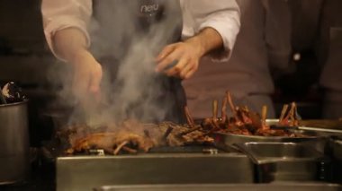 Şef pirzola pişiriyor. Ateş ve duman.