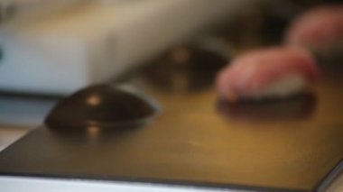 Suşi şefi bir parça ton balığı ve pirinç suşisi hazırlıyor.