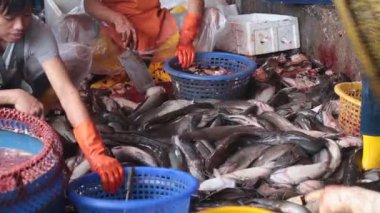 Kasap kanlı yerde balık kesiyor.