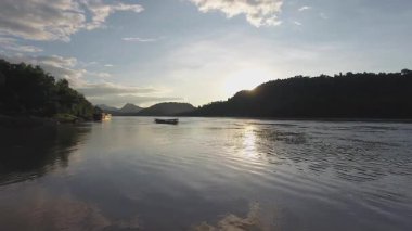 Gün batımında Laos nehrinde tahta bir tekne.