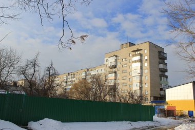 Bir kış günü Sovyet döneminden kalma yeşil metal çitlerin arkasındaki apartmanda. Çıplak ağaçlar, kar ve kentsel çevresi olan bir Doğu Avrupa şehrinde tipik bir yerleşim yeri..