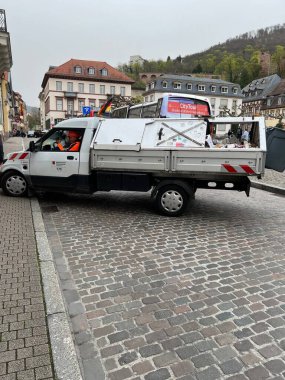 Tarihi bir Avrupa şehir merkezinde, kaldırım taşı sokağında çalışan işçiyle birlikte küçük bir kamu hizmetleri kamyonu. Kentsel bakım ve kamu hizmetleri kavramı.