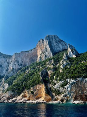 İtalya 'nın Sardunya kıyısındaki Akdeniz' in üzerinde dramatik kireçtaşı dağları ve uçurumlar yükseliyor. Engebeli kayalar, yeşillik ve sakin mavi sularla doğal manzara..