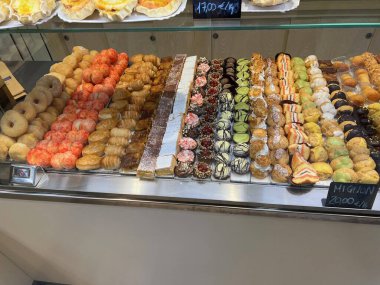 Fiyat etiketli bir pastane vitrininde çeşitli İtalyan hamur işleri ve tatlıları sergileniyordu. Avrupa 'daki bir pastanede geleneksel tatlılar ve mignon hamur işleri.