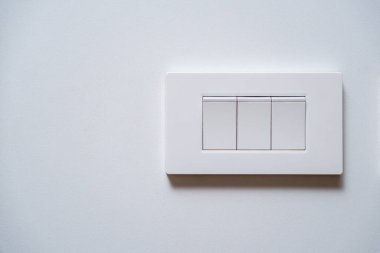 Temiz beyaz bir duvarda fotokopi alanı olan modern beyaz bir üçlü ışık düğmesi. Minimalist iç tasarım ve elektrik kavramı.