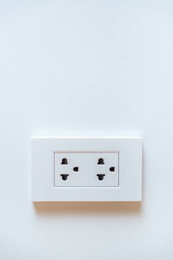 Temiz beyaz bir duvarda, fotokopi alanı olan çift prizli beyaz bir elektrik prizi. Güç kaynağı kavramı ve ev iç tasarımı.