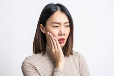 Güzel, genç Asyalı hasta bir kadının portresi izole edilmiş beyaz arka planda ağrıyan yanağa baskı yapıyor, akut diş ağrısı, periodontal hastalık, çürük ya da çene ağrısı çekiyor. Diş sorunları konsepti.