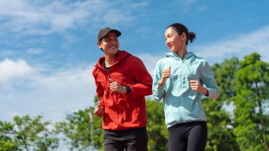 Genç Asyalı çift sabahları dışarıda koşuyor ve park geçmişleri var. Sağlıklı koşu ve açık hava egzersizlerini hesaba katın..