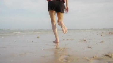 Koşan kadın günbatımında hayatın ve özgürlük plajının tadını çıkarıyor. 4k çözünürlüğü.