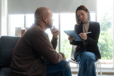 Asyalı bir adam akıl sağlığı kliniğinde Asyalı kadın psikoloğa danışmanlık yapıyor. Psikolog not alıyor ve depresyondaki erkek hastalarla konuşuyor..