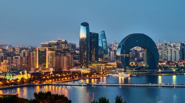 Bakü, Azerbaycan. Günümüz Bakü ufuk çizgisinin gece görüşü. Yansıtılmış kıyı şeridi ve ikonik yüksek binaların mimarisi Hazar Denizi 'ni yansıtıyor. Akşam Bakü Bulvarı.