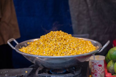 Taze buğulanmış mısır büyük bir metal kasede üst üste yığılmış, bir sokak yemeği standında servis edilmeye hazır..