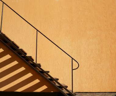 Sarı desenli duvarda geometrik gölgeler olan minimalist dış merdiven.