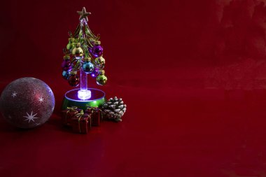 Kırmızı arka planda hediyeler yazan Noel ağacı. Noel baloları, Noel ağacı ve hediyeler..