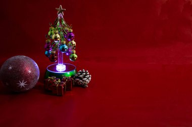 Kırmızı arka planda hediyeler yazan Noel ağacı. Noel baloları, Noel ağacı ve hediyeler..