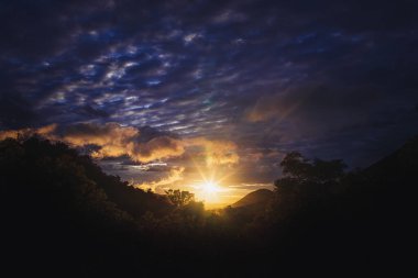 Gün batımında dağların manzarası, sıcak altın ve turuncu ışık zirveleri ve gökyüzünü boyuyor. Manzara, seyahat, macera ve ilham verici içerik için mükemmel.