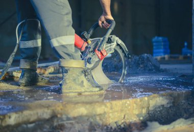 Bir işçi beton zemini beton kesiciyle kesiyor. Beton testeresi için özel bir alet. Yüksek kalite fotoğraf