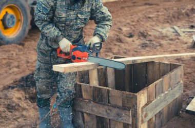 Bir adam elektrikli testere ile bir tahta kesiyor. Konuyla ilgili fotoğraflar İnşaat ve temel atma. Yüksek kalite fotoğraf