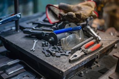 Kaynakçı bir çilingir masası, bir iş gününden sonra ekipmanlarını bırakan alet ve parçalarla doluydu. Yüksek kalite fotoğraf