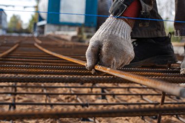 Bir işçinin eli gelecekteki tek katlı betonda takviye çubukları oluşturur. Yüksek kalite fotoğraf