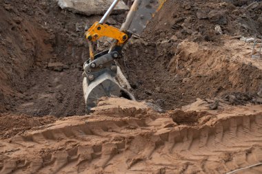 Yeraltında ince bir elektrik hattı var. İnşaat alanındaki kazıcı traktörü tellerin etrafındaki toprağı kazıyor. Yüksek kalite fotoğraf