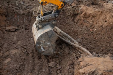Yeraltında ince bir elektrik hattı var. İnşaat alanındaki kazıcı traktörü tellerin etrafındaki toprağı kazıyor. Yüksek kalite fotoğraf
