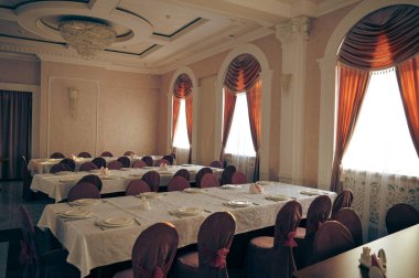 Boş bir salon, perdeleri beyaz masa örtüleri ve Roma dekoru olan klasik bir restorandır. Yüksek kalite fotoğraf