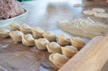 Evde köfte yaparken çekilmiş otantik bir fotoğraf. Masanın üzerinde hamur, un ve soğanlı kıyma var. Yüksek kalite fotoğraf
