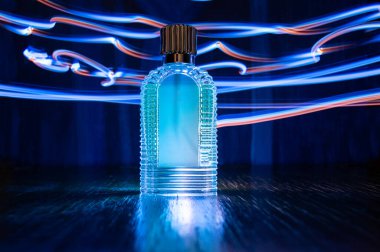 Arka planda, neon renkli izleyicilerin arka planına karşı mavi bir parıltıyla yarı karanlık ve parıltılı bir parfüm şişesi dolusu lüks reCTanGULAR GÖSTERİ. Metin pankartınızı girmekte serbestsiniz. Yüksek kalite fotoğraf