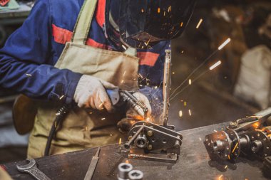 Mekanizmanın küçük parçalarını kaynak yapan bir çalışanın bulunduğu atmosferik fotoğraf atölyesi. Elektrikli trenler için endüstriyel parça üretimi. Yüksek kalite fotoğraf