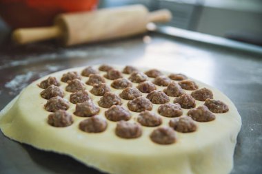 Çiğ hamurla çevrili, üzerinde kıyma parçaları olan, hamur köftesi pişirmeye hazır bir masanın yakın çekimi. Hızlı hamur köftesi üretimi için bir cihaz. Yüksek kalite fotoğraf