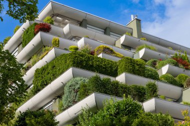 Lush Terrace Garden ve Sürdürülebilir Şehir Mimarisi ile Modern Yeşil Konut Binası. Canlı yeşillik ve katmanlı teras bahçeleriyle kaplı çağdaş konut binası. Mimari, doğa ile şehir yaşamını harmanlıyor, gösteriş yapıyor.