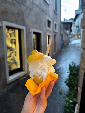 Güzel bir eski kasaba caddesinde yürürken el ele tutuşmak ferahlatıcı limonlu dondurma. Sahne yaz yolculuğunu, yerel mutfağı ve tatlı tatlı deneyimini yansıtıyor. Turizm, sokak yemekleri ve yaz yaşam tarzı kavramları için ideal.