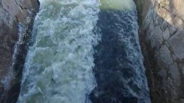 Güneşli bir günde damlalarda küçük bir gökkuşağı olan barajdan güçlü su akar.