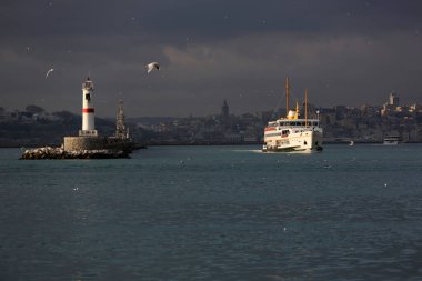 Deniz fenerinden geçen İstanbul feribotu ve martılarla birlikte gökyüzü.