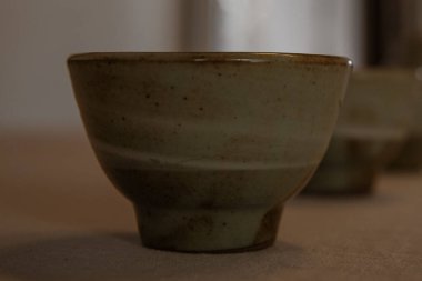 El yapımı seramik çay fincanının detaylı bir yakın plan görüntüsü. Topraksı jöle tonları, ince doku ve kapalı bir alanda bulanık bir arkaplan..