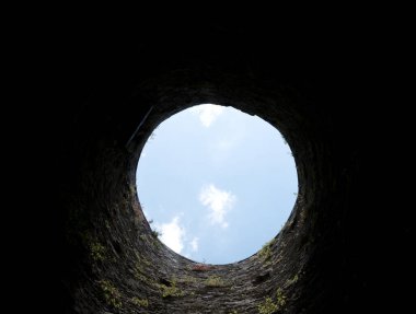 Taş kuyu çukuru, içeriden eski yapı, tuğla duvarlar ve mavi gökyüzü arka planı, kuyu kavramına göre çöker.
