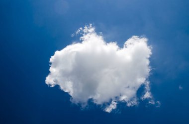 Derin mavi yaz gökyüzünde uçan tek beyaz kabarık bulut