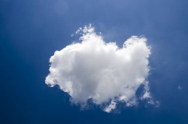Derin mavi yaz gökyüzünde uçan tek beyaz kabarık bulut
