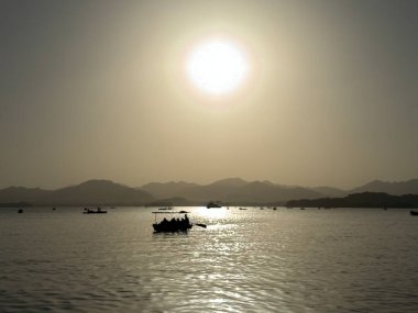 Çin 'in Hangzhou kentindeki Batı Gölü' nün günbatımı manzarası, sakin su ve sıcak akşam ışığı, seyahat ve doğa kullanımı için uygun.