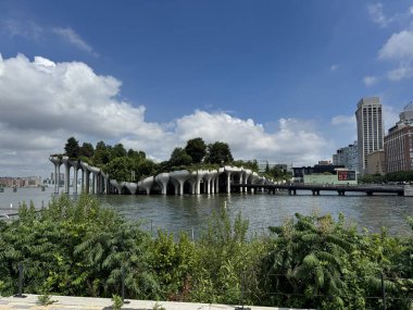New York 'taki Little Island, Hudson Nehri üzerine inşa edilmiş, kendine özgü lale şekilli beton sütunları, yükseltilmiş peyzaj yolları ve Manhattan ufuk çizgisinin panoramik manzarası olan çağdaş bir halk parkı. Tasarım mimariyi, doğayı harmanlıyor..