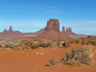 Kızıl çöl tabanından yükselen kumtaşı popolarının olduğu Anıt Vadisi 'nin dramatik çöl manzarası. Amerika 'nın güneybatısının ikonik manzarası engin gökyüzünü, engebeli jeolojiyi ve Navajo kabile parkının ebedi güzelliğini ön plana çıkarıyor..